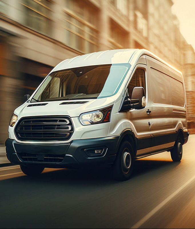White ford transit van driving on a road with a blurred background