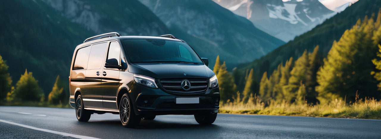 Black Mercedes-Benz metris van on a mountain road with trees and mountains in the background